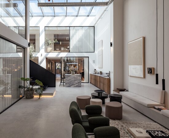 Norma Franck office in Marbella, featuring a modern double-height interior with floor-to-ceiling windows, sleek black staircase, and elegant natural finishes.