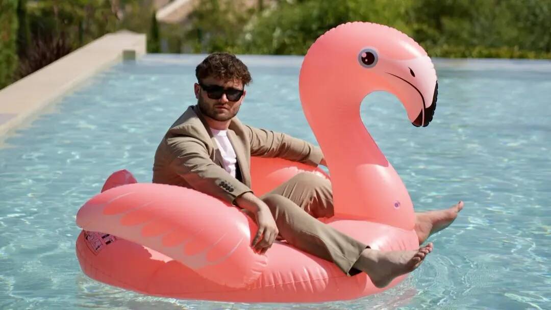 Man in a suit on a flamingo float in a swimming pool