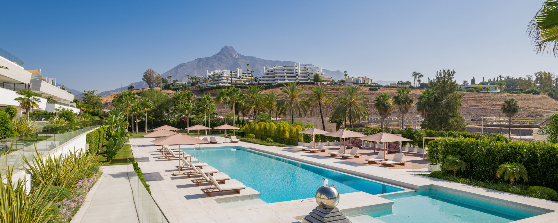 Luxury villa swimming pool in Marbella with mountain views, landscaped gardens and sun loungers