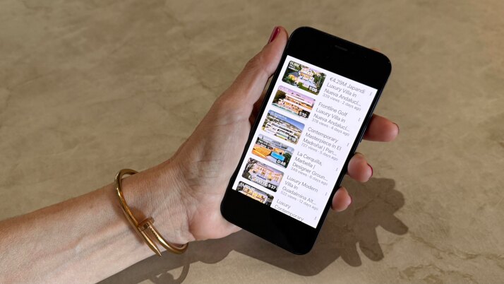 Smartphone displaying Marbella Hills Homes YouTube channel with luxury villa video listings, illustrating digital marketing performance and content-driven property exposure