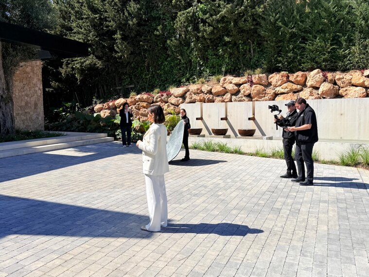 Team of Marbella Hills Homes filming a luxury property in Marbella, featuring Evelin Bentz presenting in a contemporary villa setting with professional video crew and outdoor modern architecture.