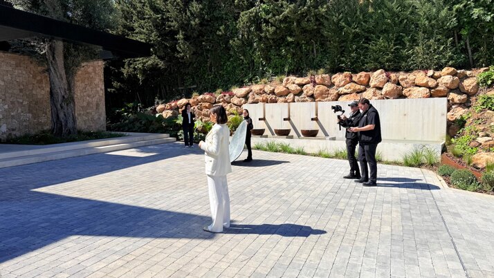 Team of Marbella Hills Homes filming a luxury property in Marbella, featuring Evelin Bentz presenting in a contemporary villa setting with professional video crew and outdoor modern architecture.