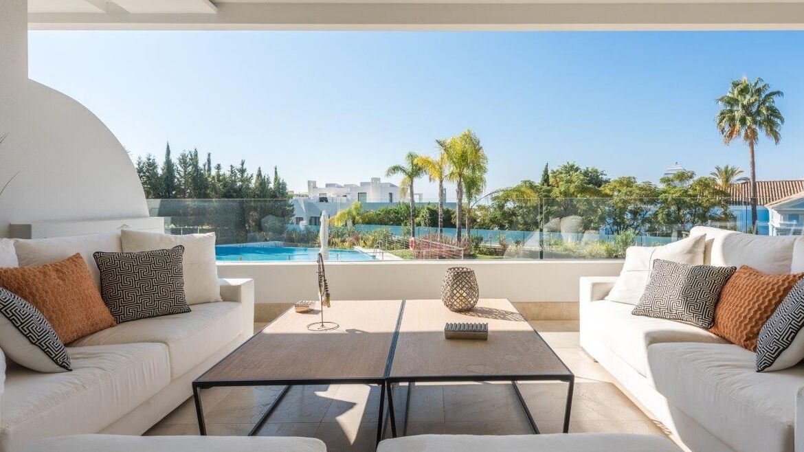 Überdachte Terrasse eines Gartenduplex mit Blick auf Gemeinschaftsgärten und Pool