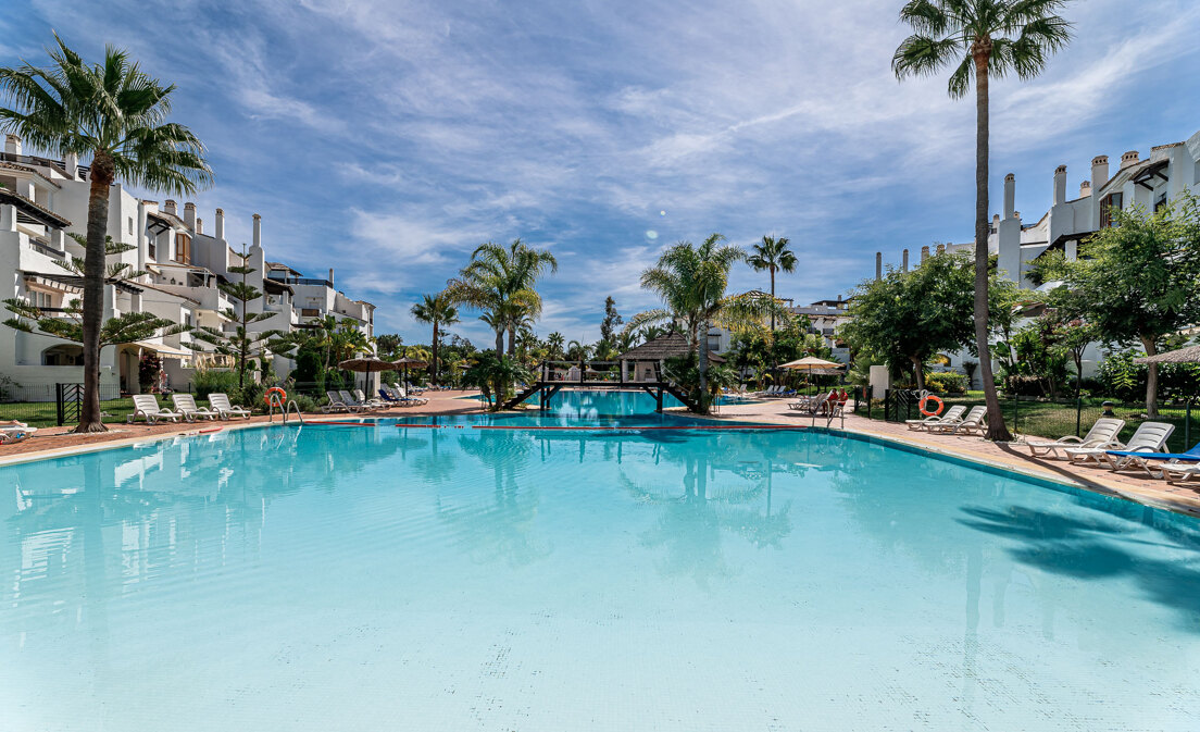 Apartamento esquinero en primera línea de playa con amplio jardín en urbanización cerrada prestigiosa