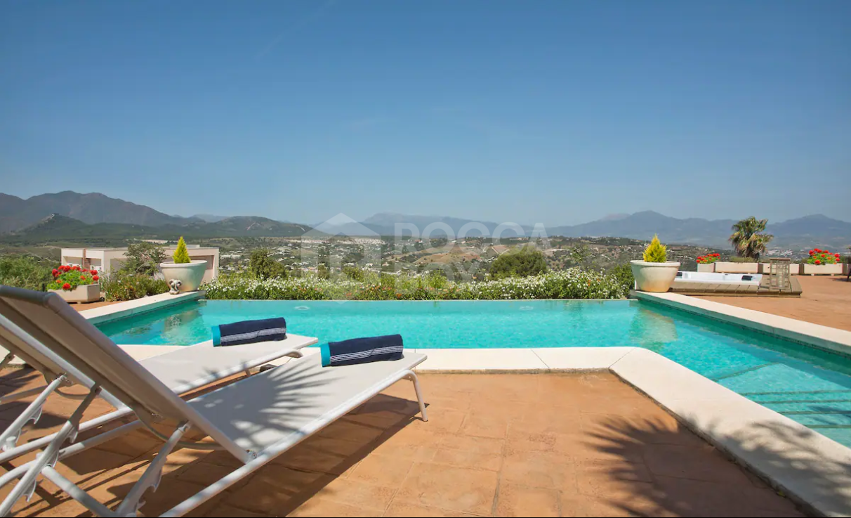 Luxury Spanish villa nestled against a pine forest with panoramic mountain views.