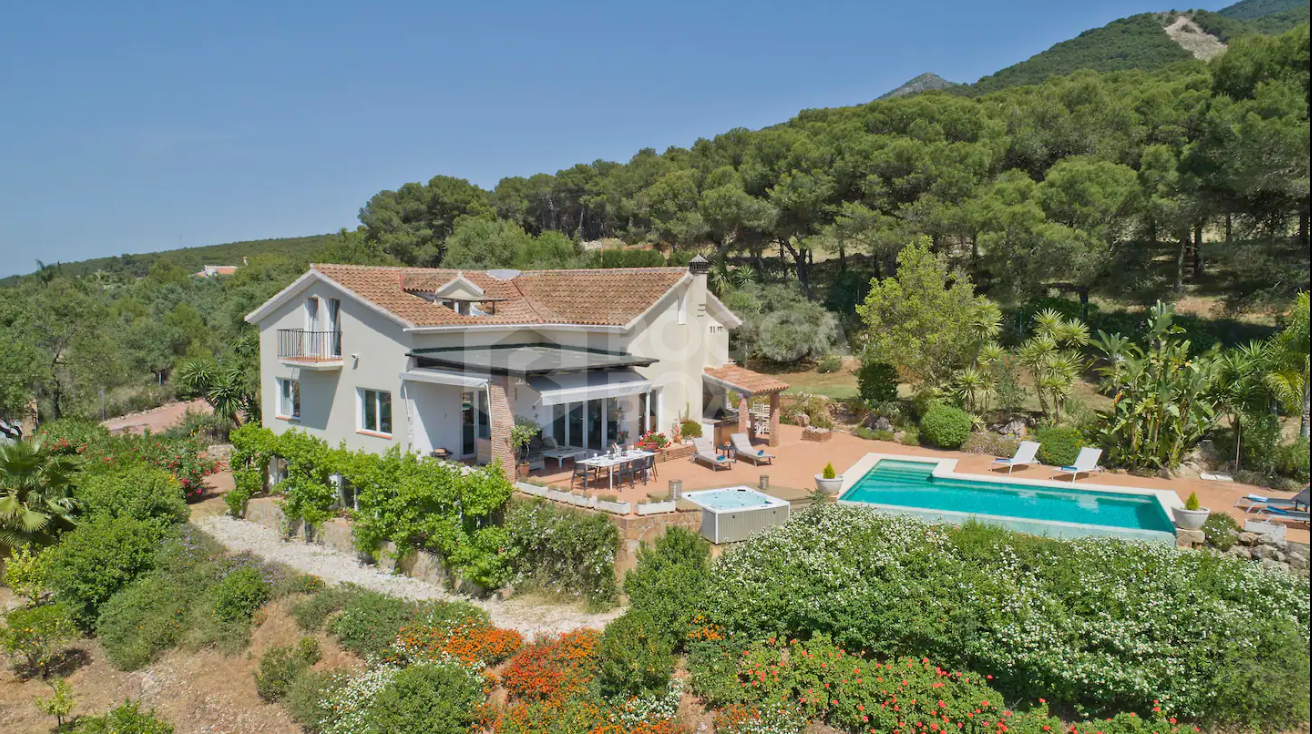 Luxury Spanish villa nestled against a pine forest with panoramic mountain views.