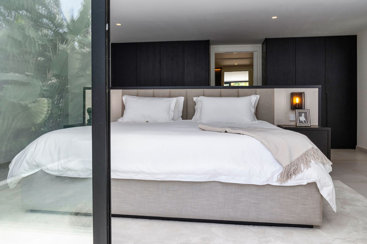 Bedroom with a large bed, dark wood built-in cabinets, and a glass door leading outside.