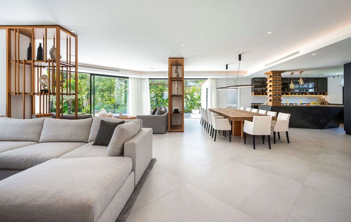 Open concept living space with sectional sofa, dining area, and kitchen visible through large windows.