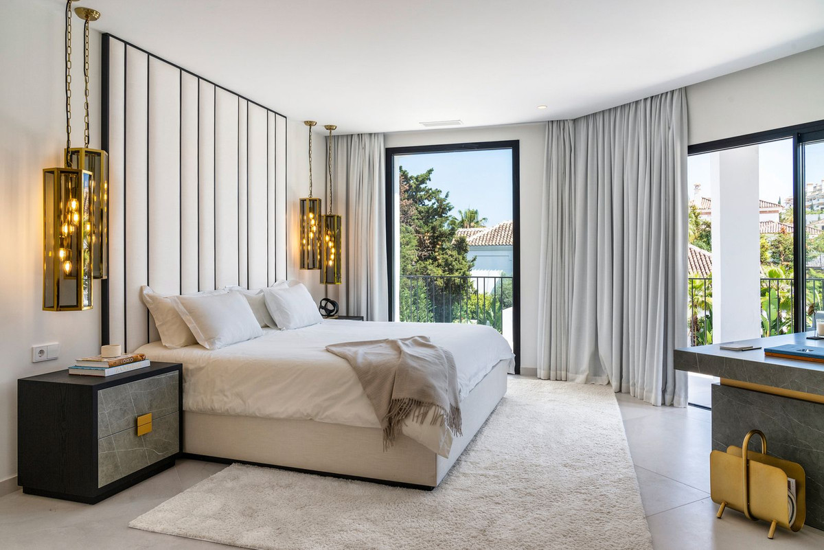Bedroom with a large white bed, black and white striped headboard, and two hanging amber pendant lights.