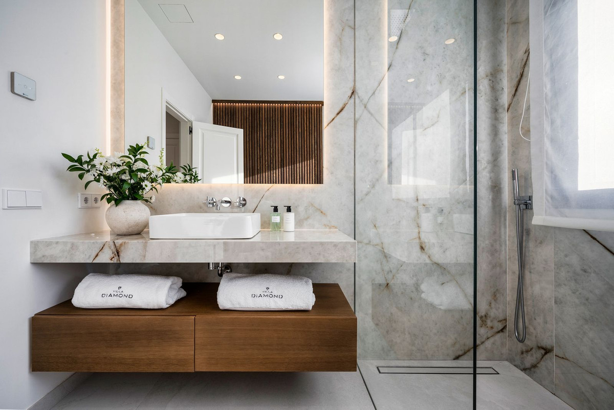 Bathroom vanity with white marble, a rectangular sink, wooden cabinet, and a large mirror.