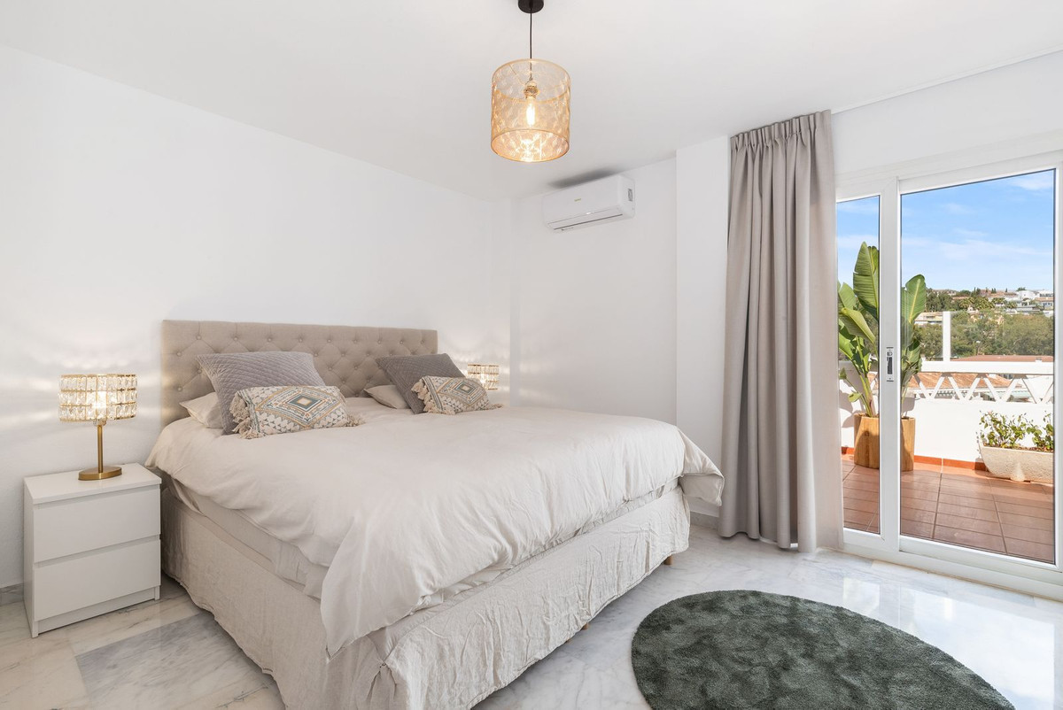 Bright master bedroom with large bed, two nightstands, and glass doors opening to a balcony.