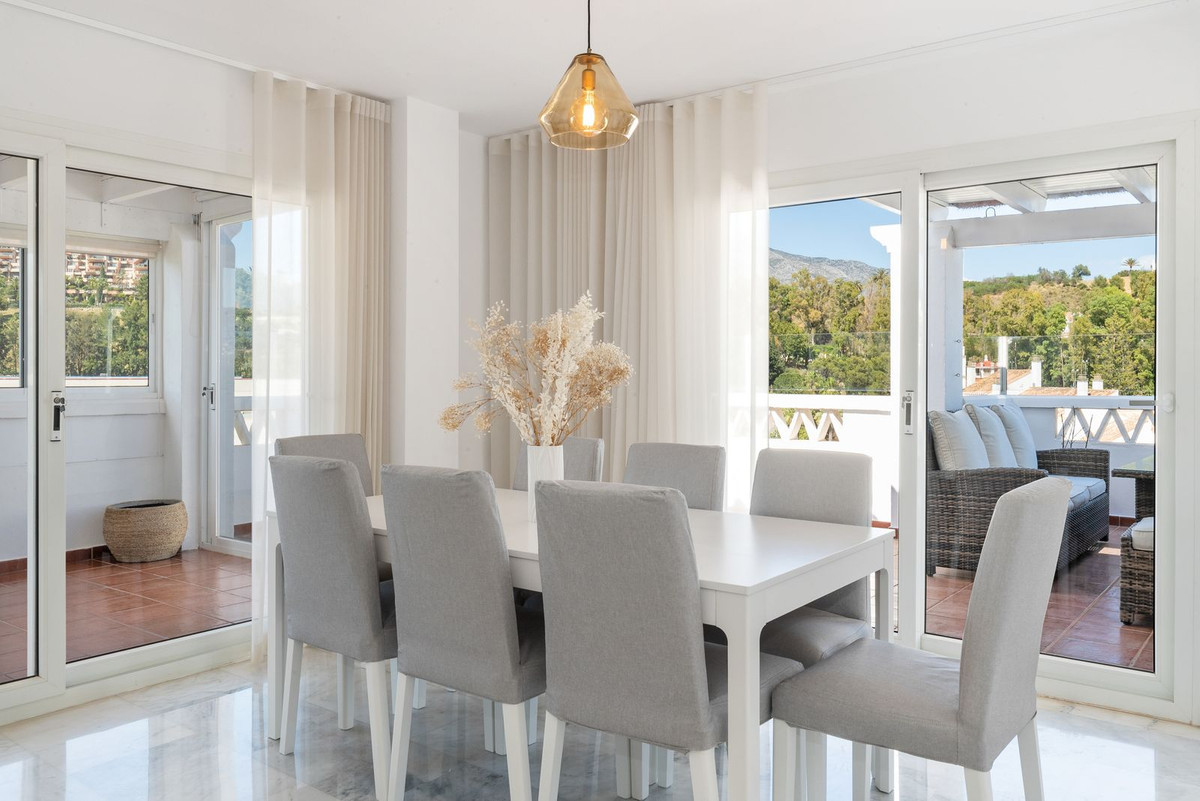 Dining room with white table, grey chairs, glass sliding doors to balcony, and outdoor views.