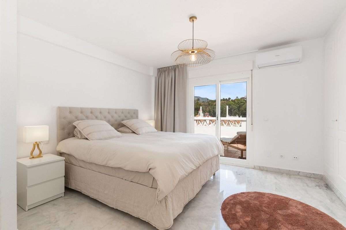 Bedroom with a large bed, tufted headboard, white side table, and direct access to a terrace.