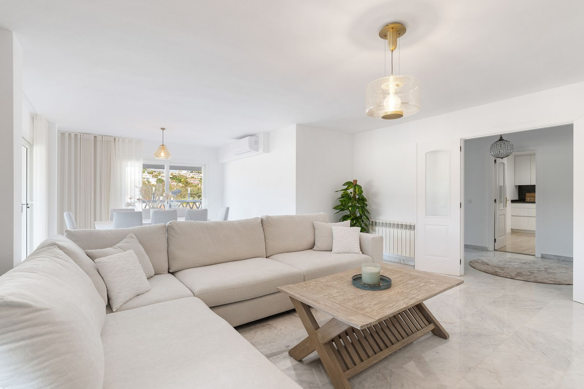 Bright living room with large L-shaped sofa, coffee table, and view into dining area.