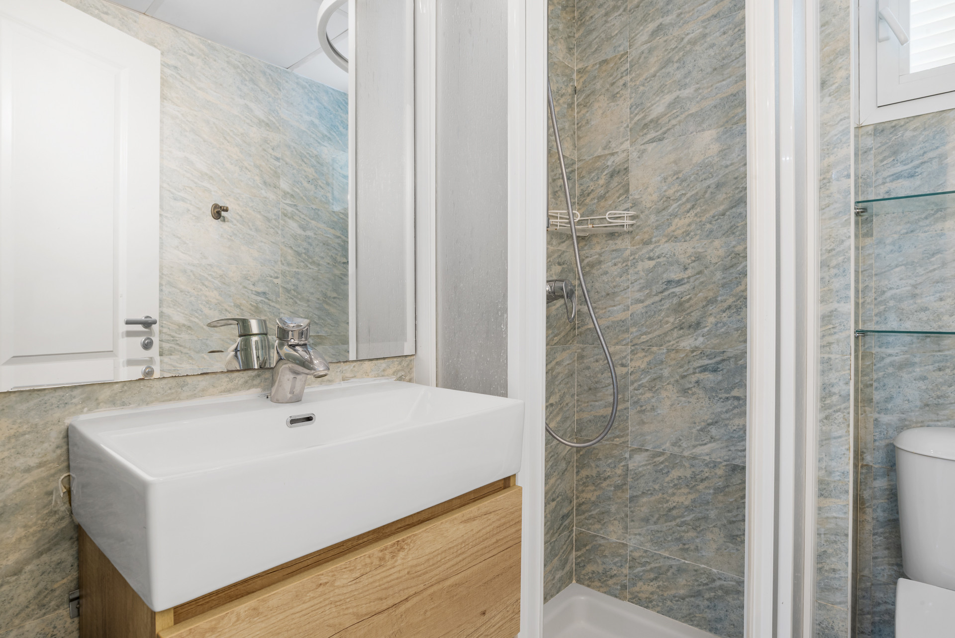 Bathroom with a white vanity sink, a large mirror, and a tiled walk-in shower stall.