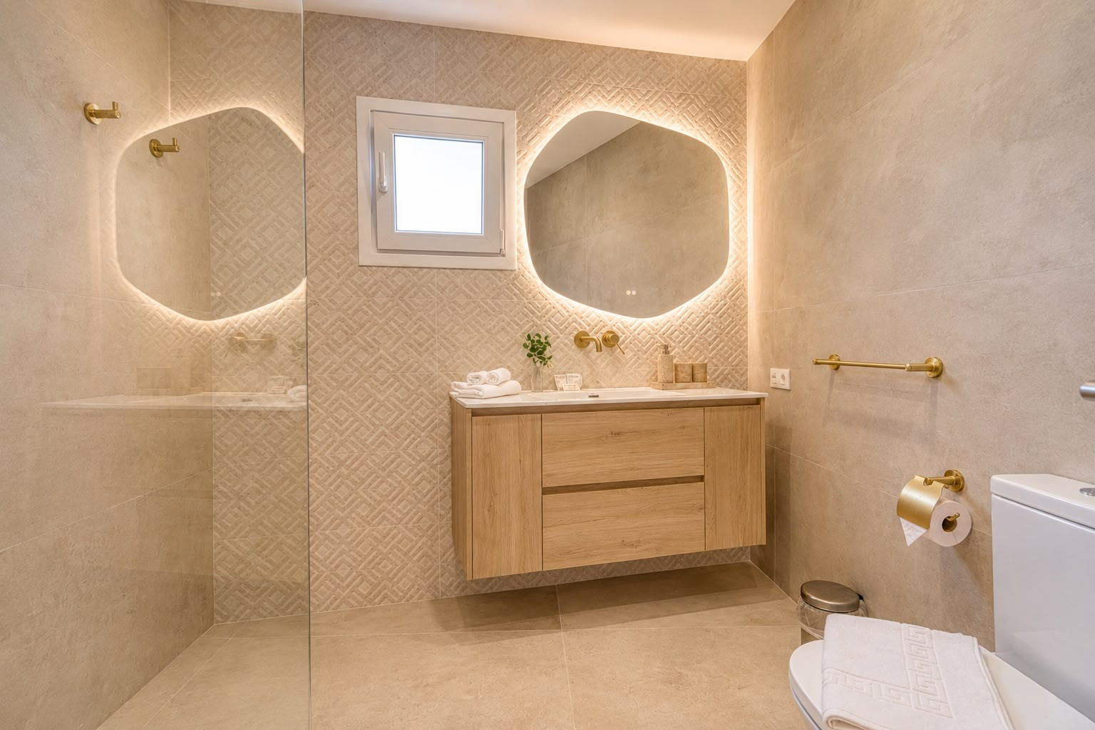Modern bathroom with walk-in shower, wooden vanity, backlit irregular mirror, and beige tiled walls.