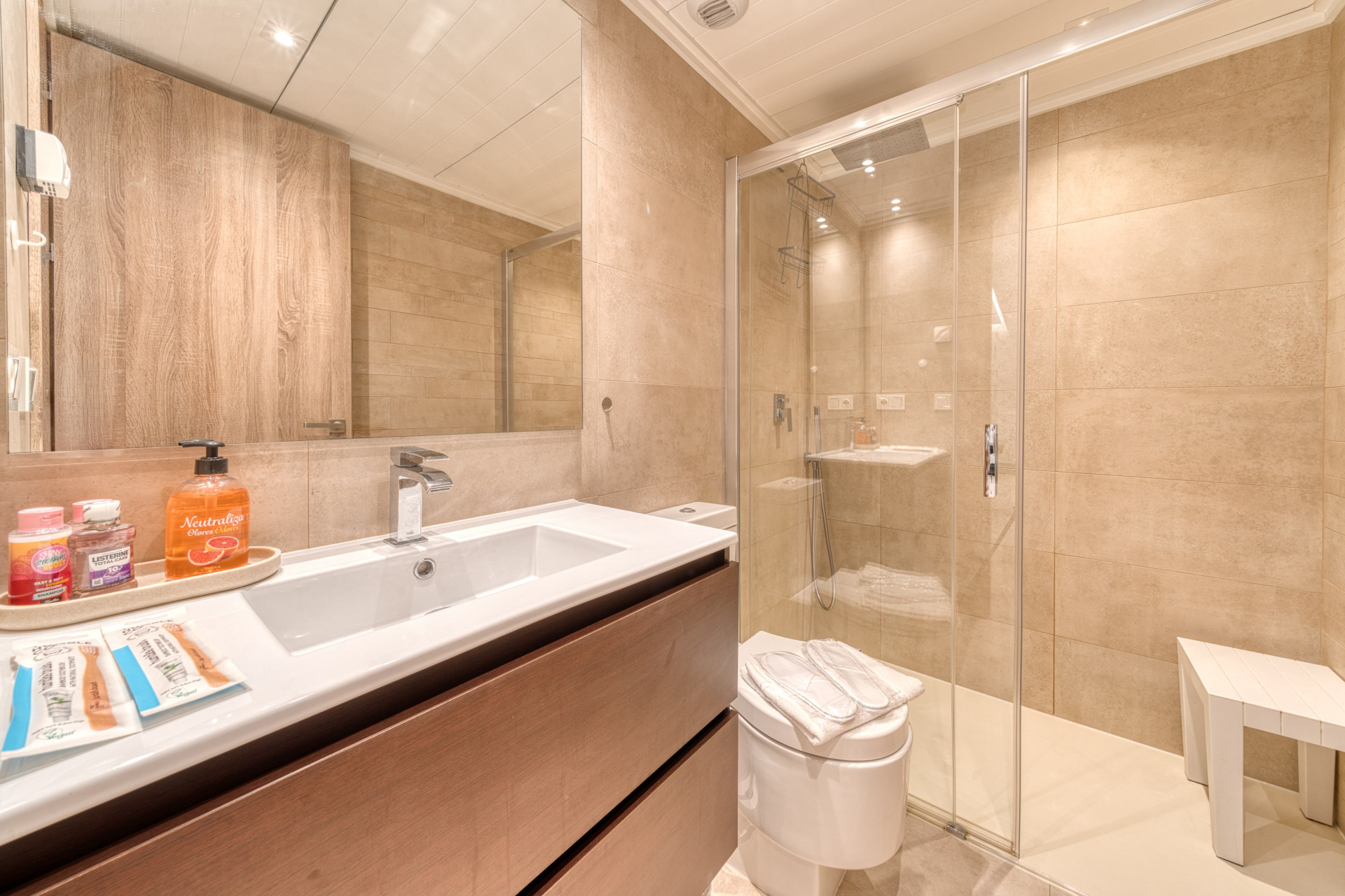 Bathroom with a wooden vanity, white sink, large mirror, and glass shower enclosure.