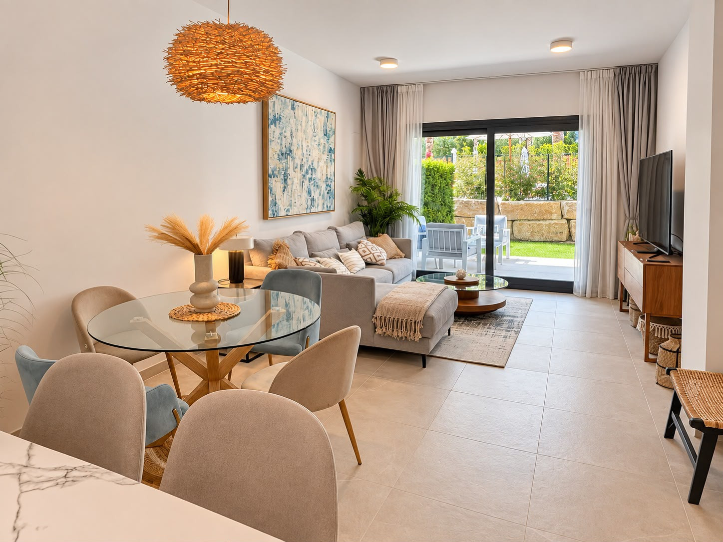 Living room and dining area with glass sliding doors leading to an outdoor patio and garden.