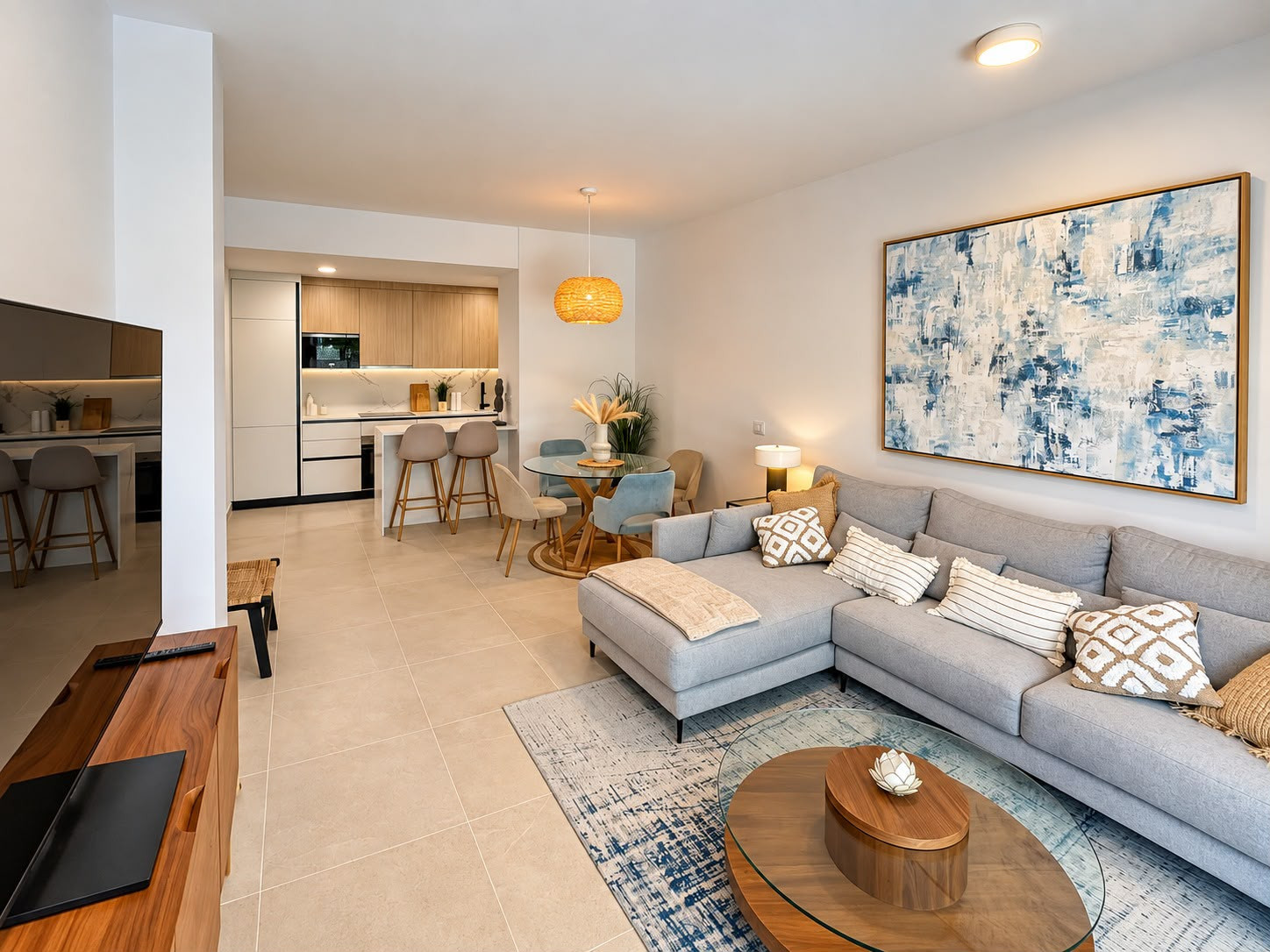 Open concept living room with grey L-shaped sofa, dining table, and kitchen bar.