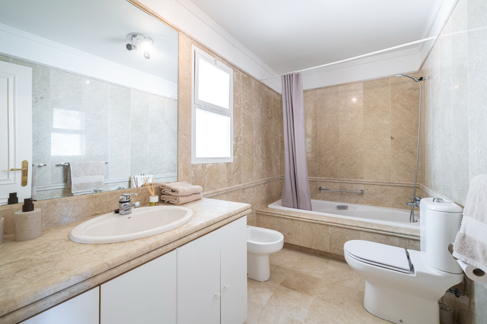 Bathroom featuring a bathtub, natural light from windows and stone finishes.