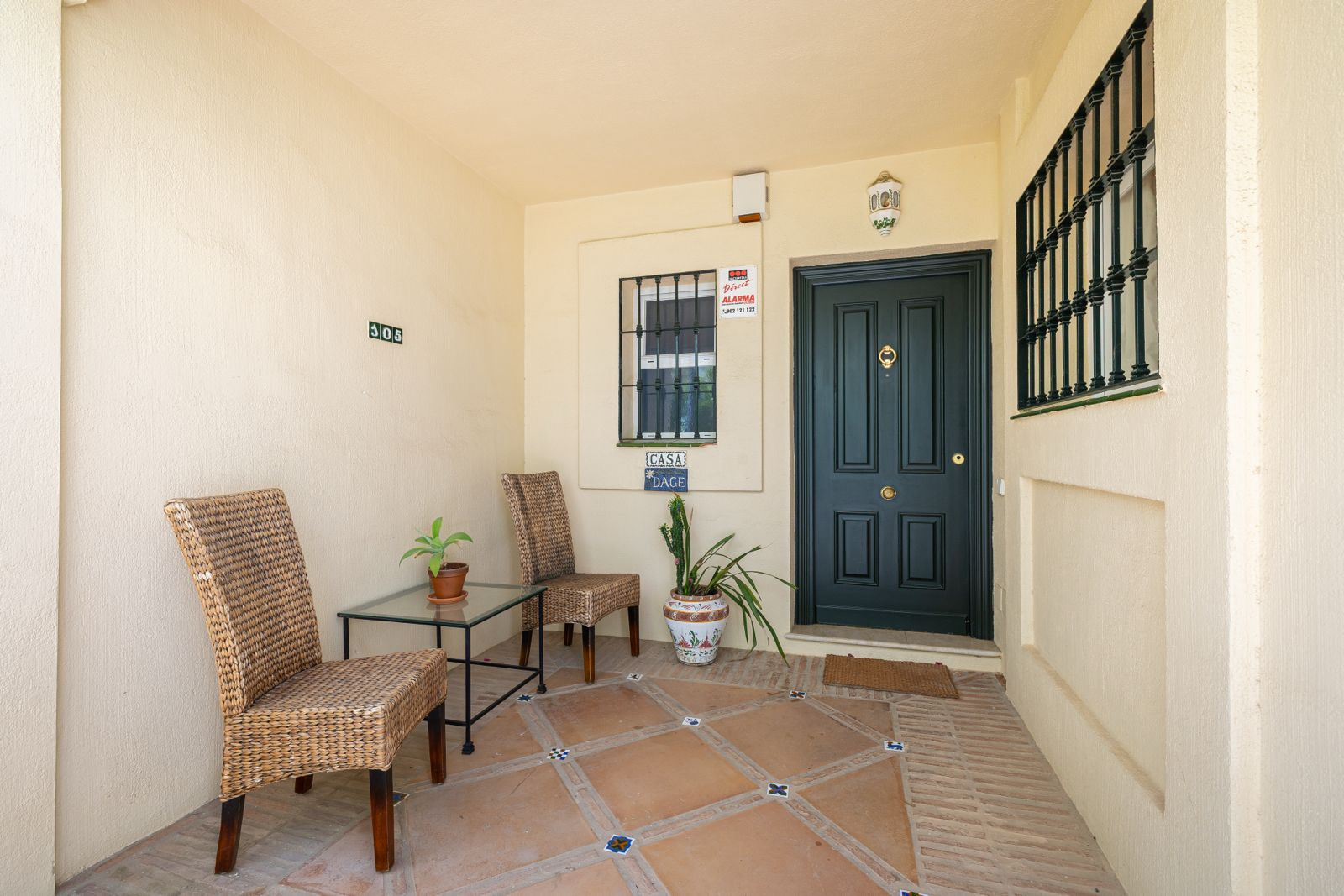 Front porch with two chairs and a table beside the entrance door.
