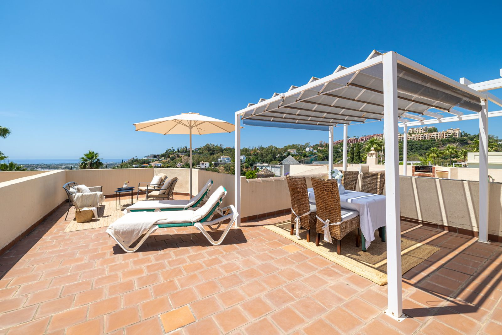 Rooftop terrace with sun loungers, dining table, and a pergola for shade.