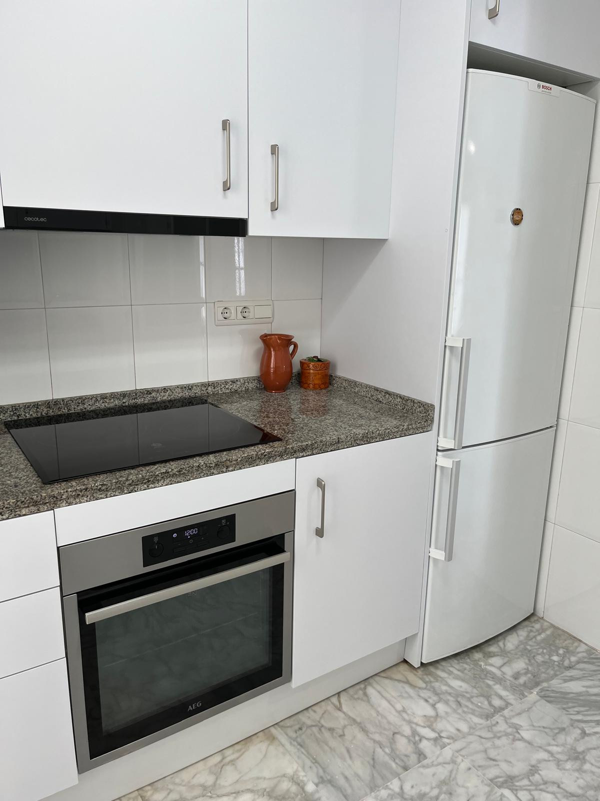Well-equipped kitchen with appliances including oven and refrigerator, clean and organized.