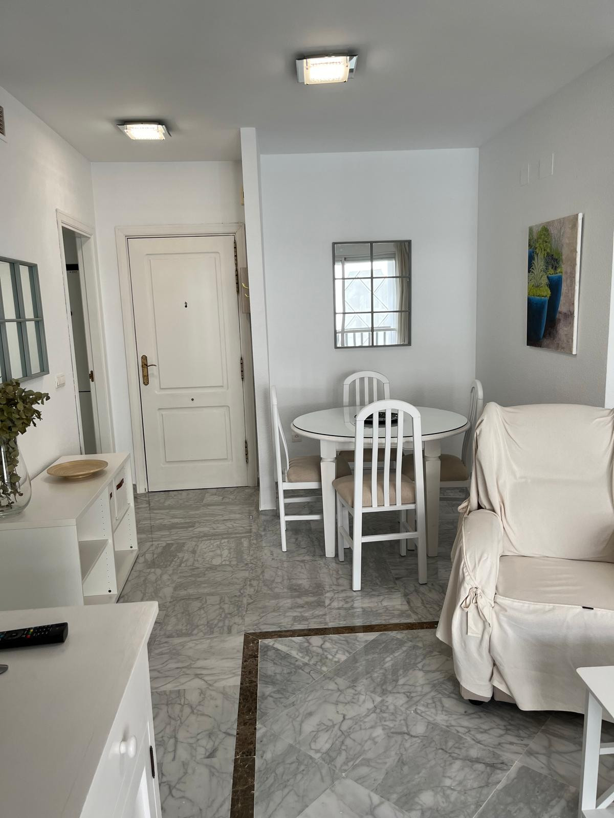 Living area with dining table and chairs, marble floor, and entrance door visible.