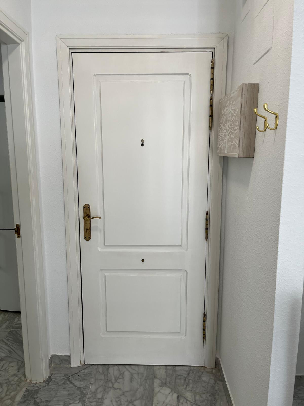 White front door with a keyhole and a small mailbox beside it.