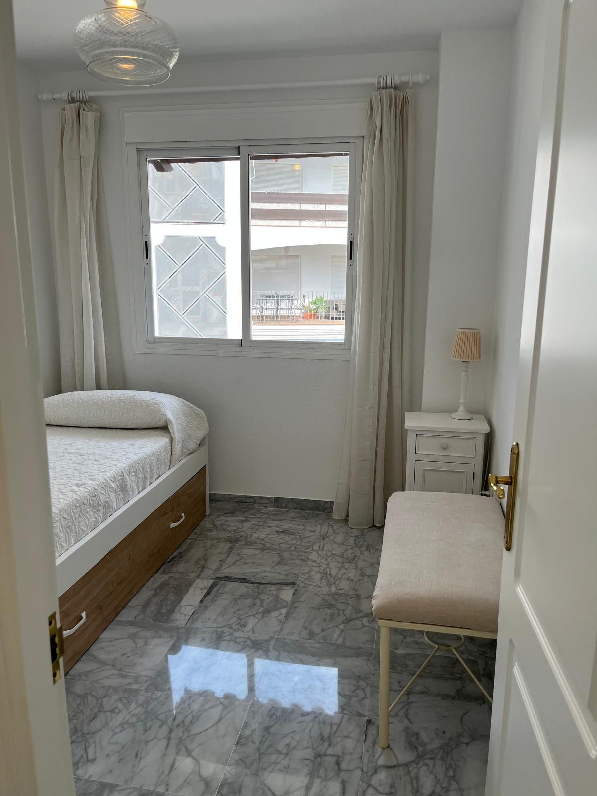 Second bedroom featuring a bed, chair, and natural light from window.