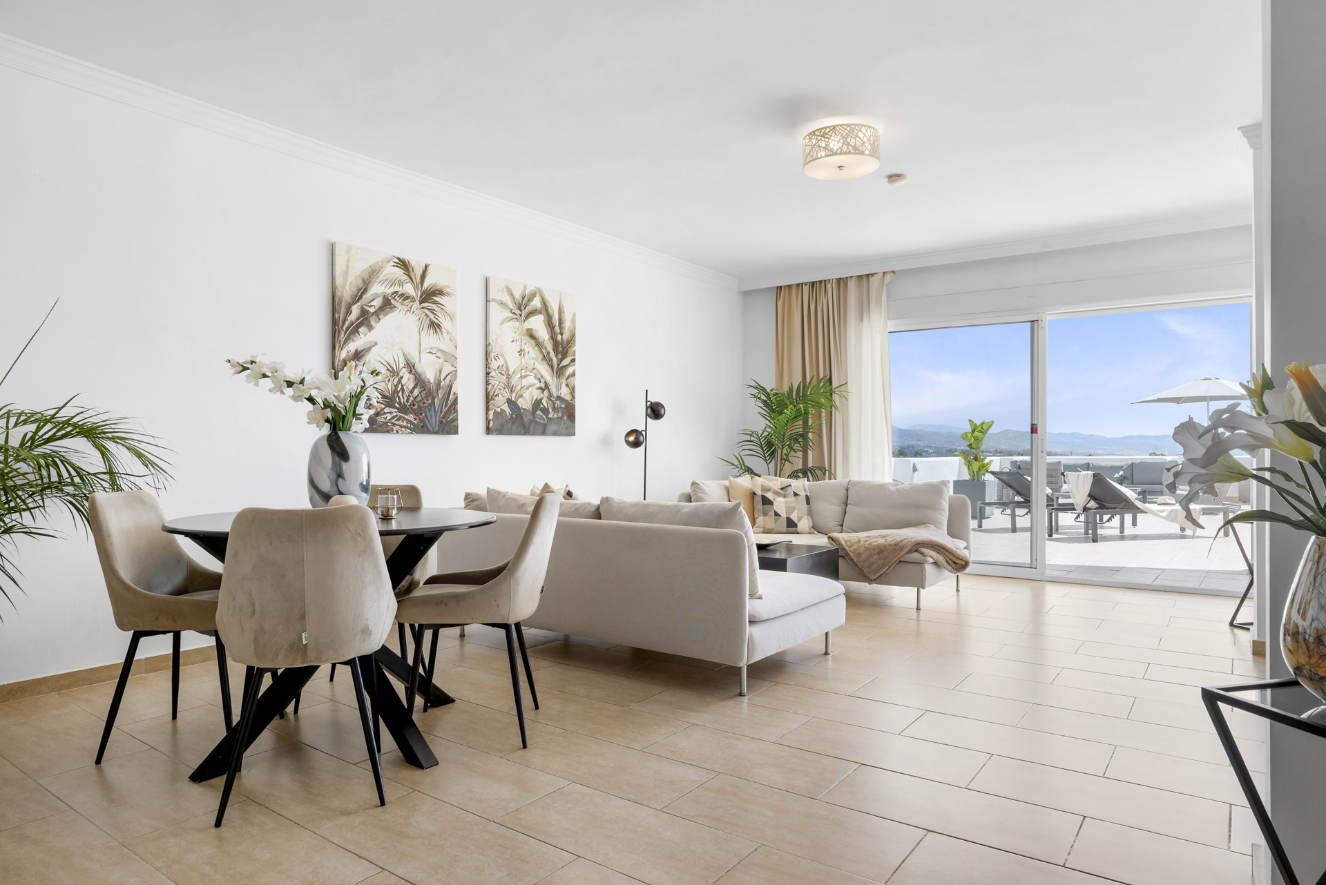 Dining area with a round table, upholstered chairs, and wall artwork in a bright open space.