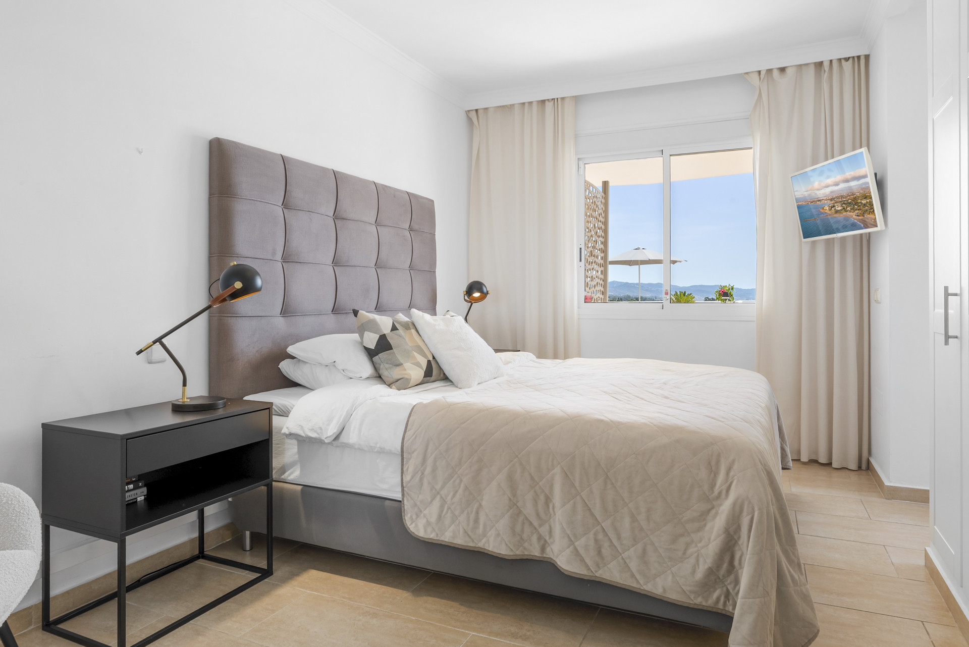 Cozy bedroom featuring a bedside table and large window with views.