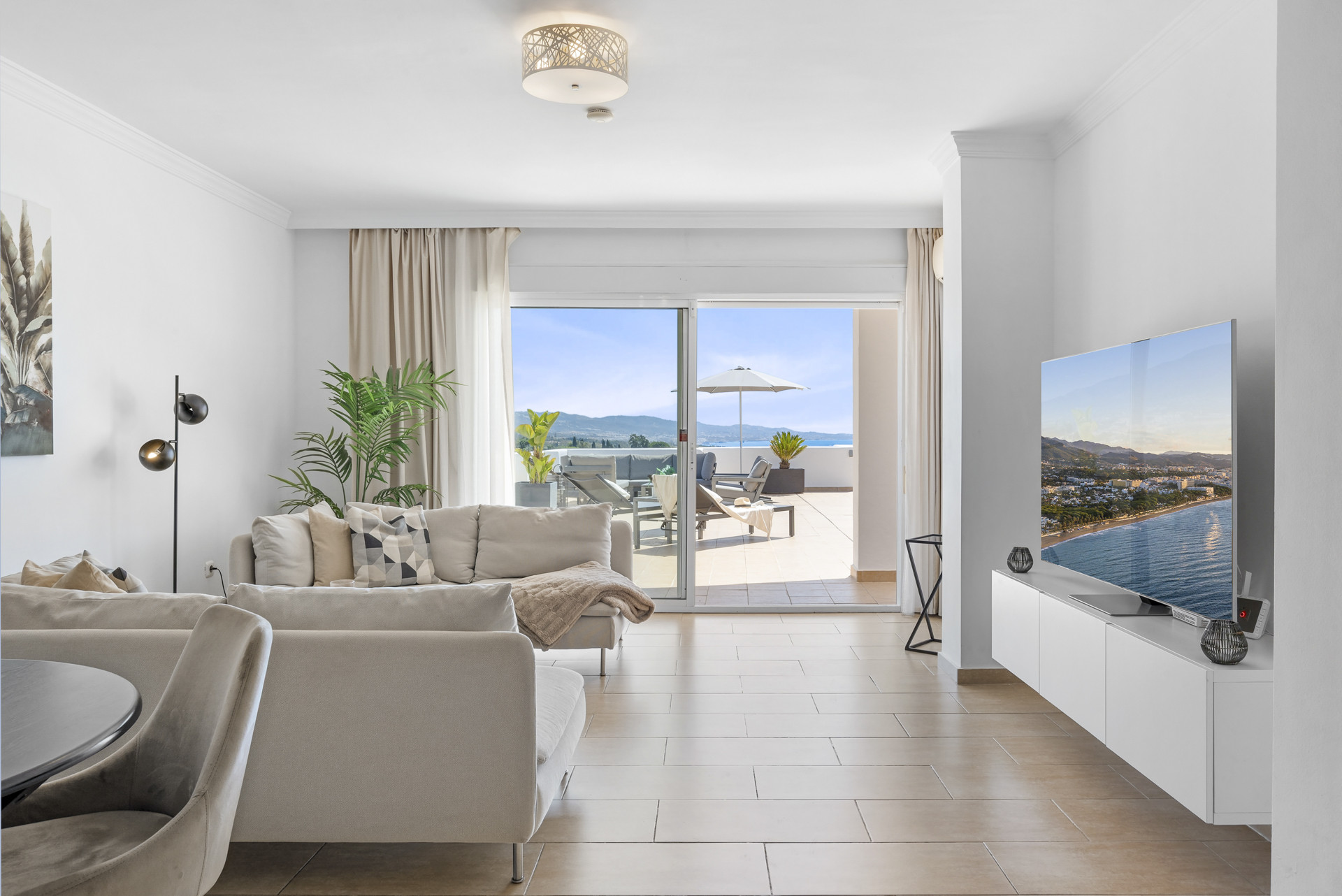 Living room featuring a sofa, TV, and sliding glass doors to a terrace with outdoor seating.