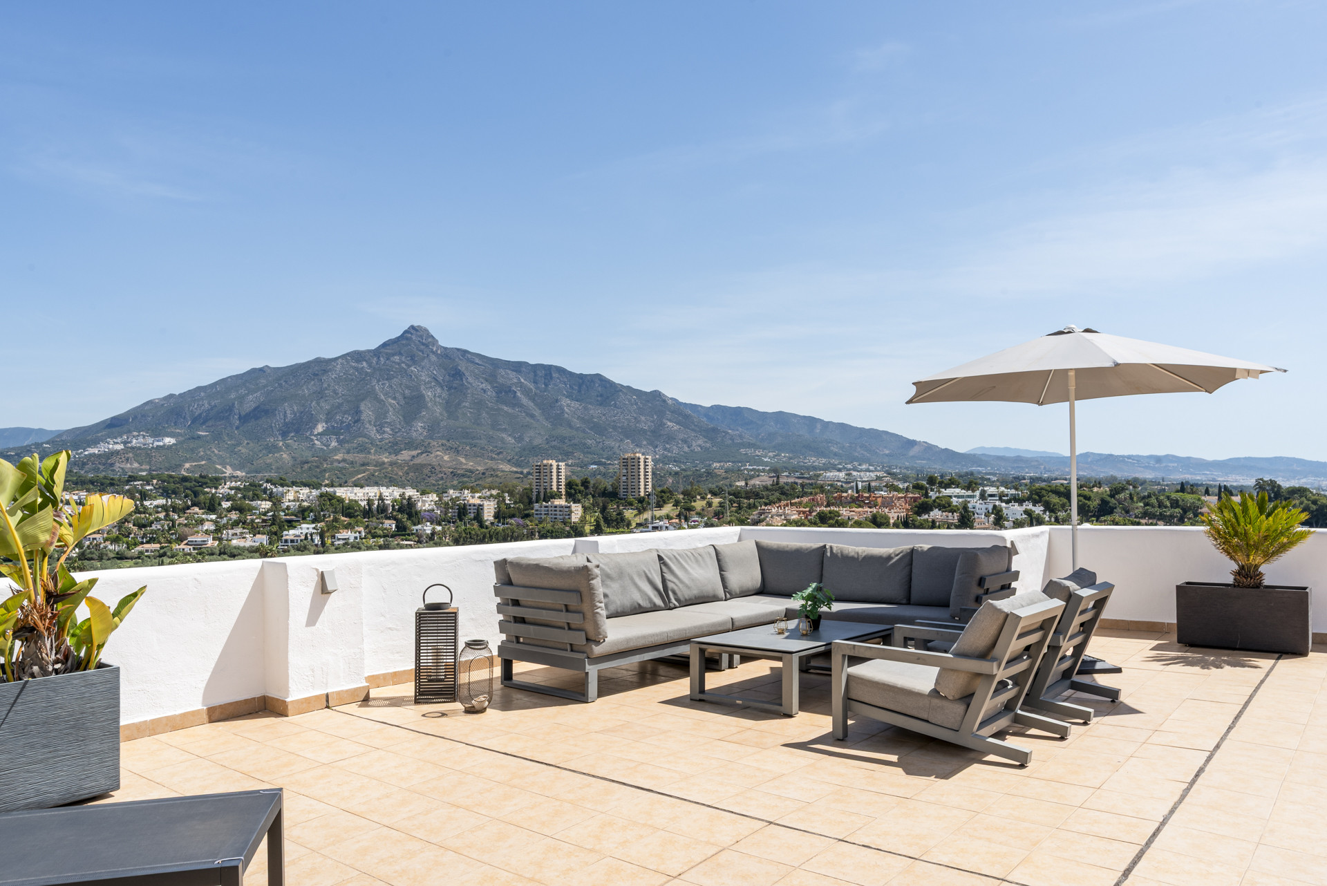 Large terrace with seating and mountain views under clear blue sky.