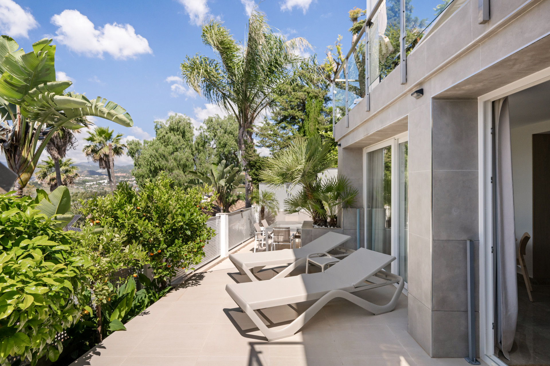 Terrace with lounge chairs surrounded by greenery.