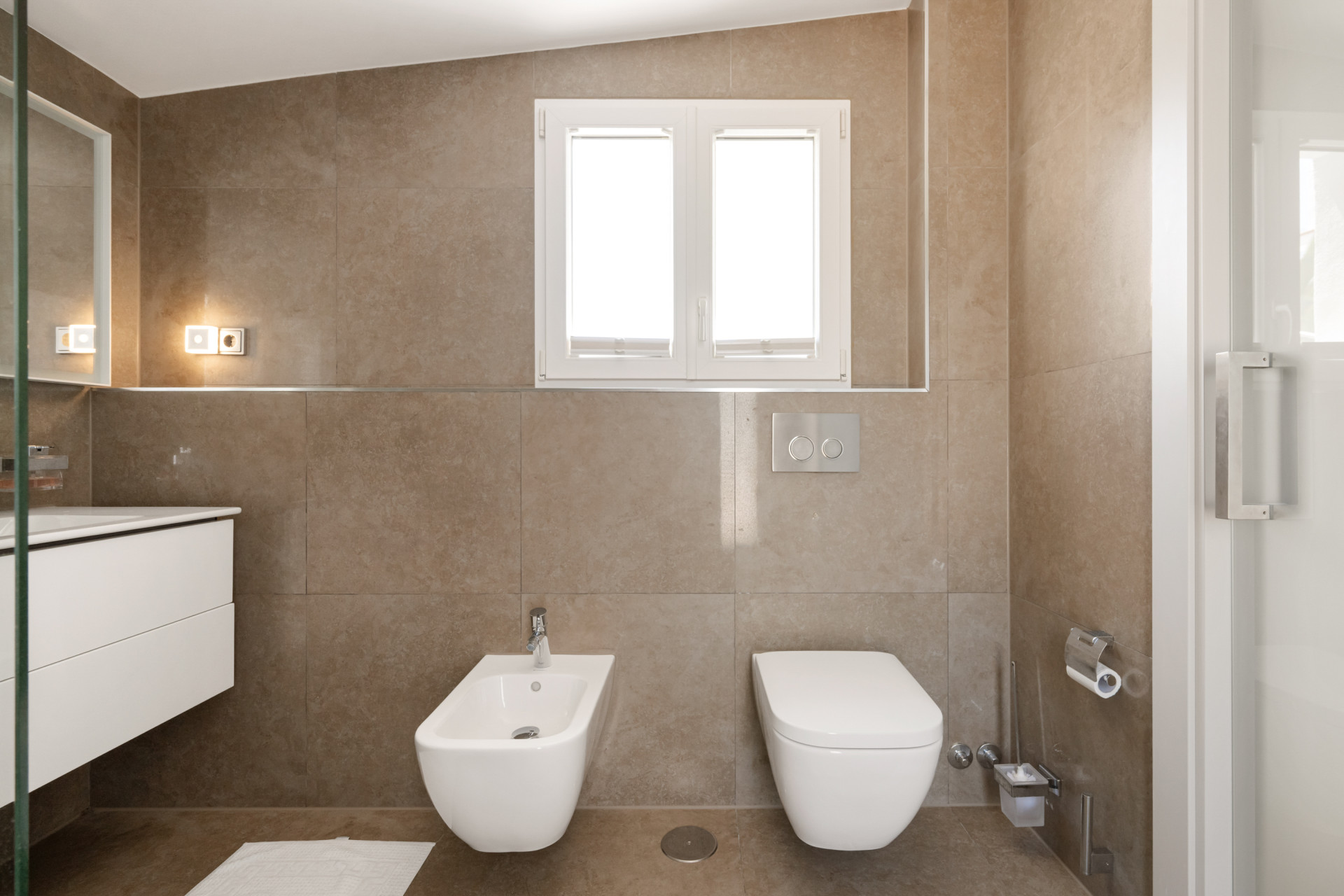 Modern bathroom featuring a bidet and window for natural light.