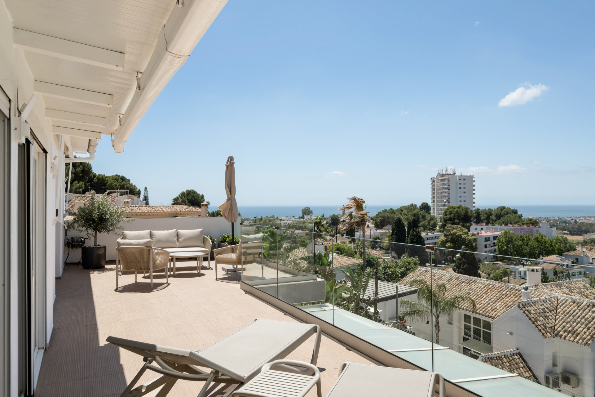 Expansive terrace with seating and sea views under clear blue skies.