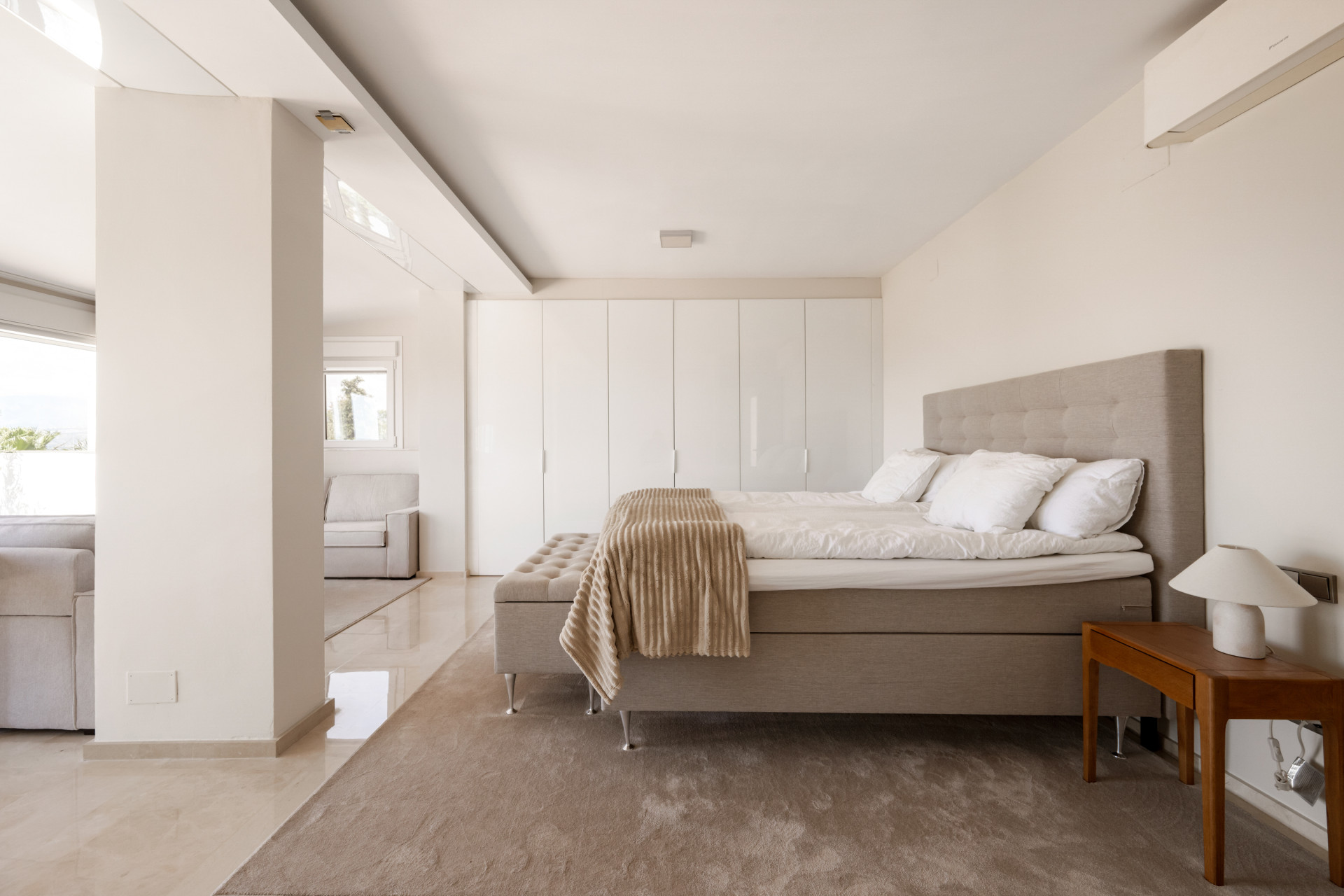 Bright bedroom with bedside table and large wardrobe storage.