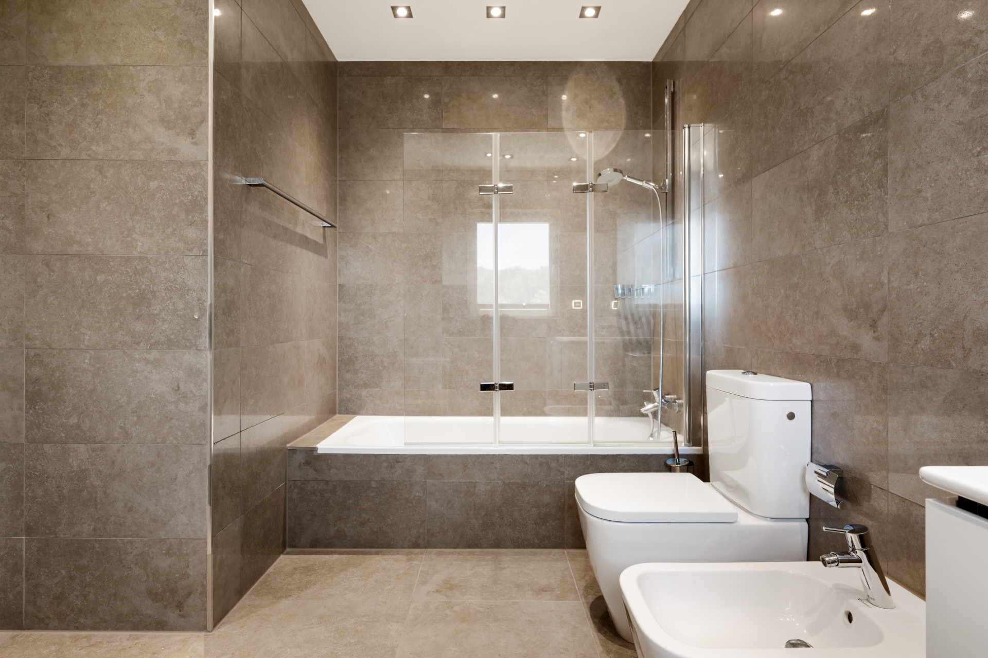 Bathroom featuring a shower and tub, tiled walls, and modern amenities.