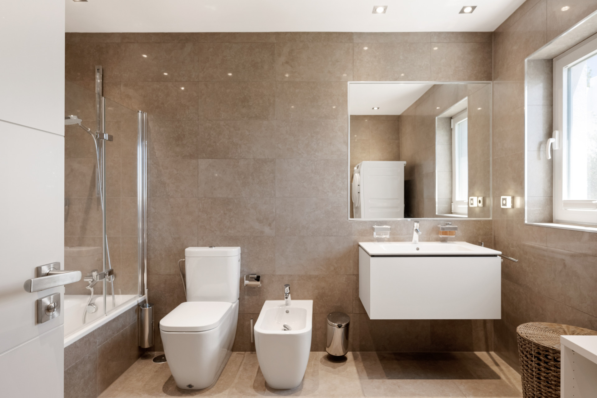 Modern bathroom with beige tiles, separate shower, and sleek fixtures.