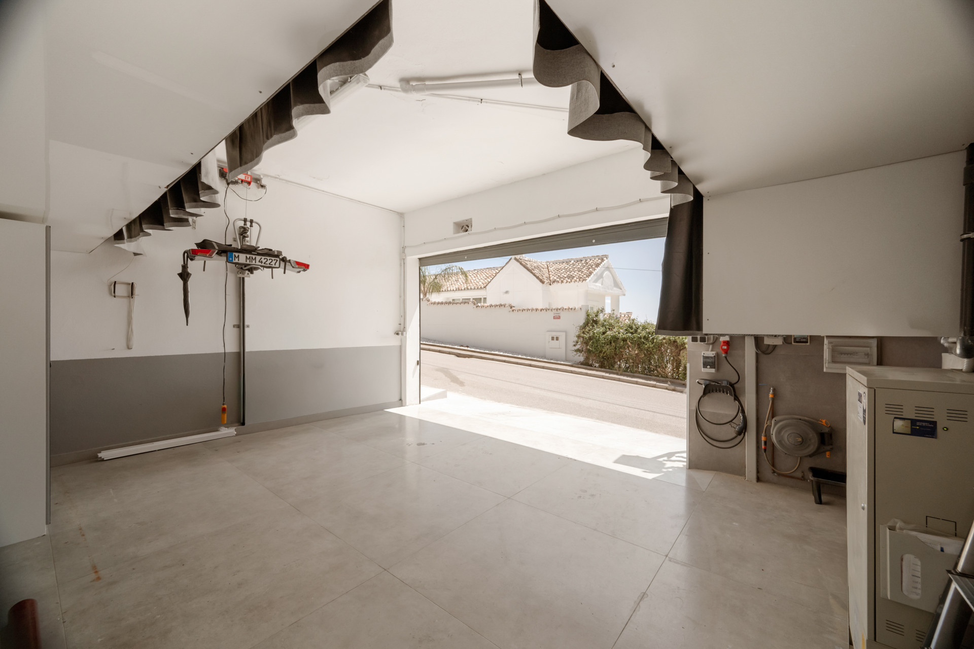 Spacious garage with open door, showcasing polished concrete floor and ceiling lights.