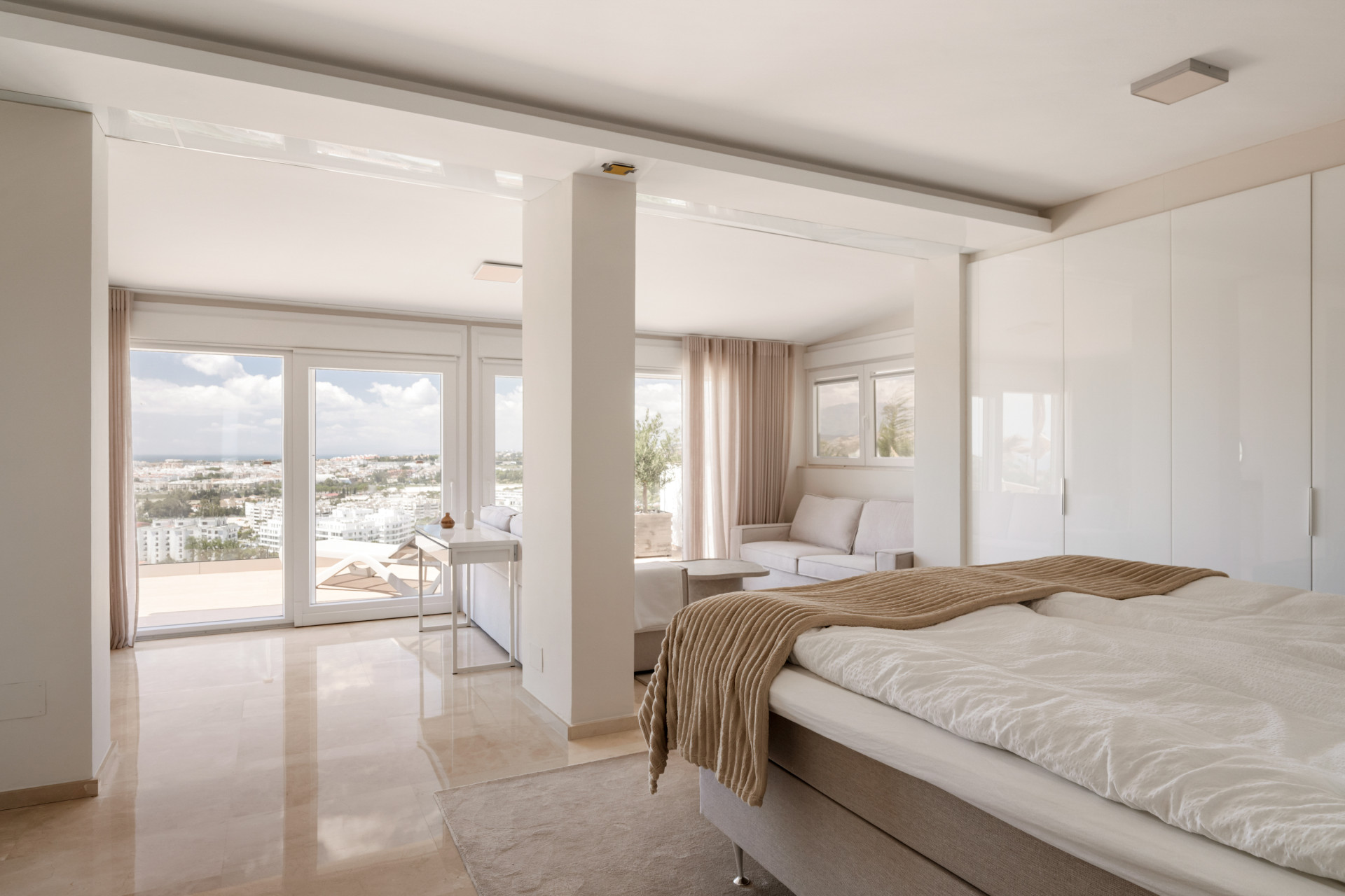 Spacious bedroom showcasing a sitting area with panoramic view windows.