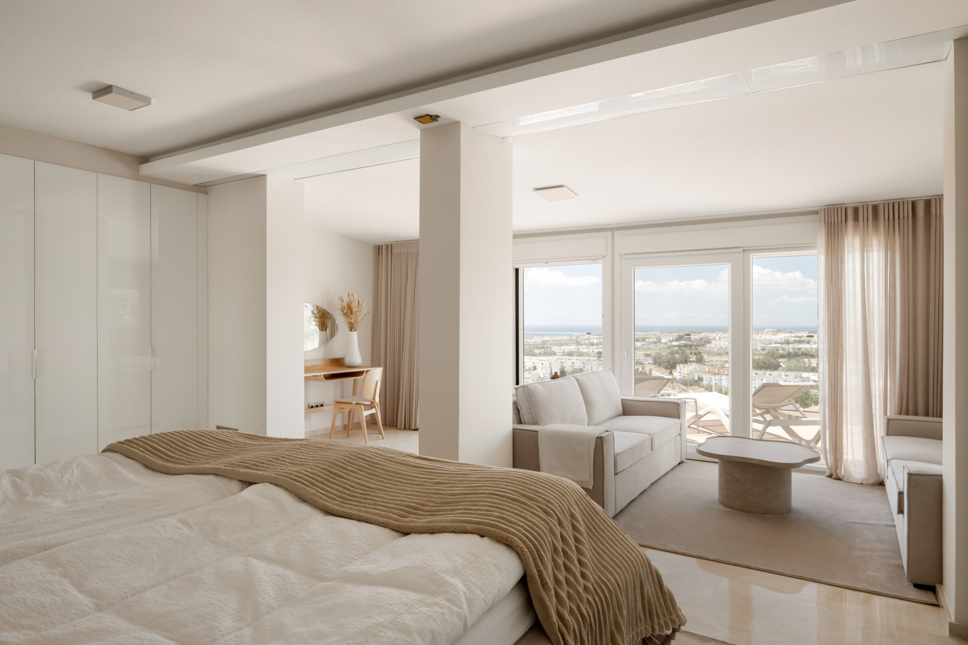 Open living space with desk and seating area, showcasing a view of the outside.