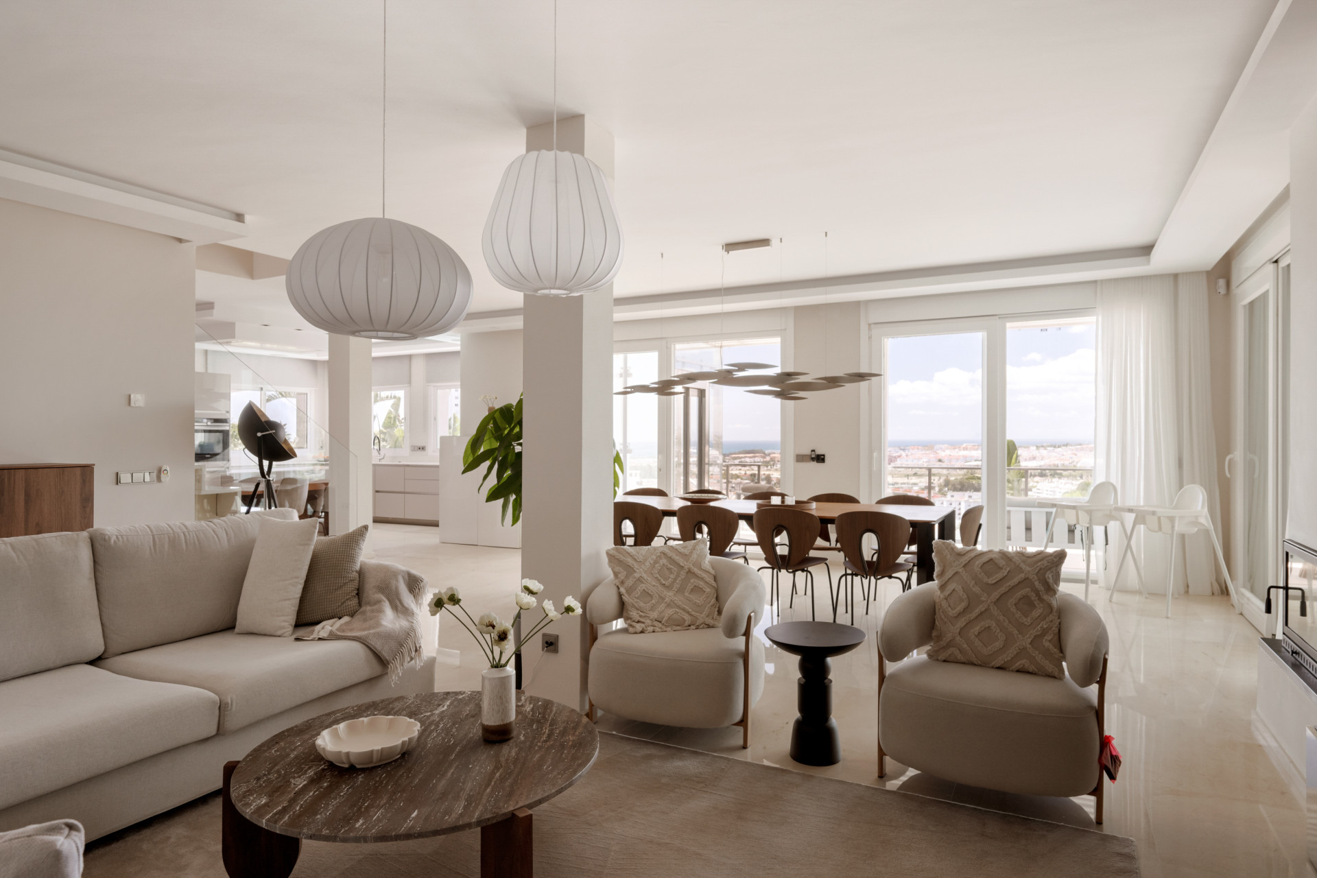 Open concept living and dining area with views of the outdoor space and stylish light fixtures.