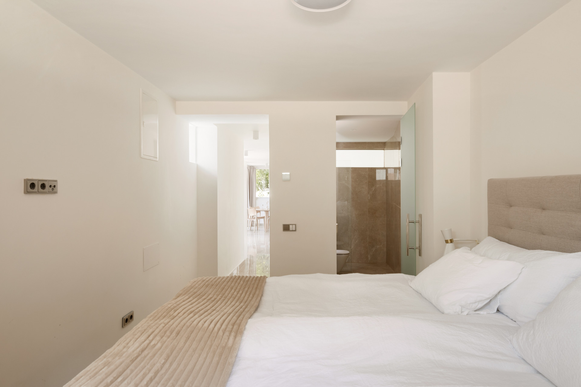 Cozy bedroom with a large bed and an adjoining bathroom visible in the background.