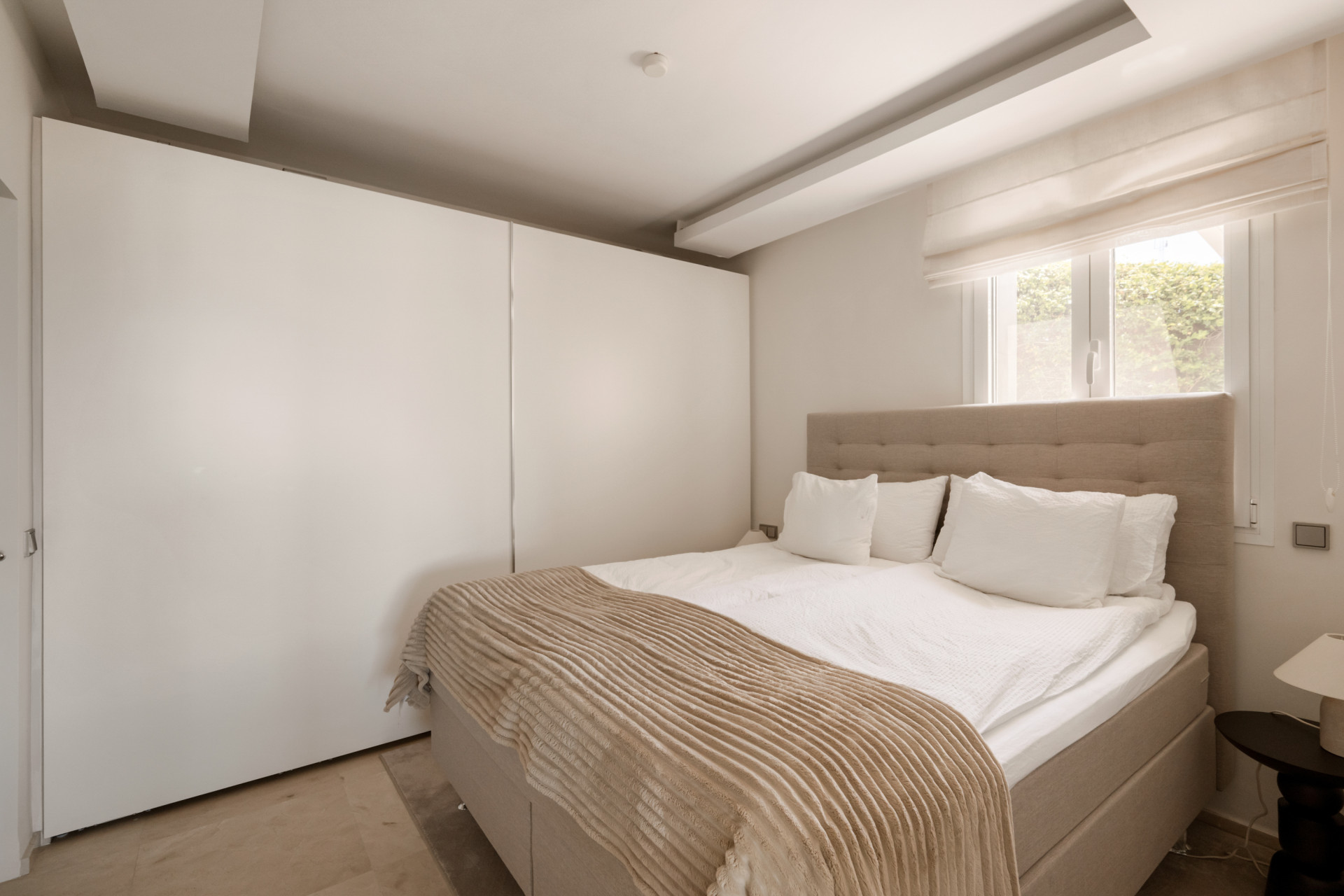 Cozy bedroom with a double bed and built-in wardrobe against light-colored walls.