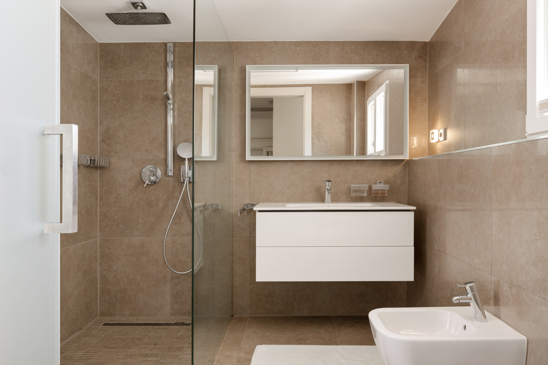 Bathroom with a shower area, sleek cabinetry, and large mirror.