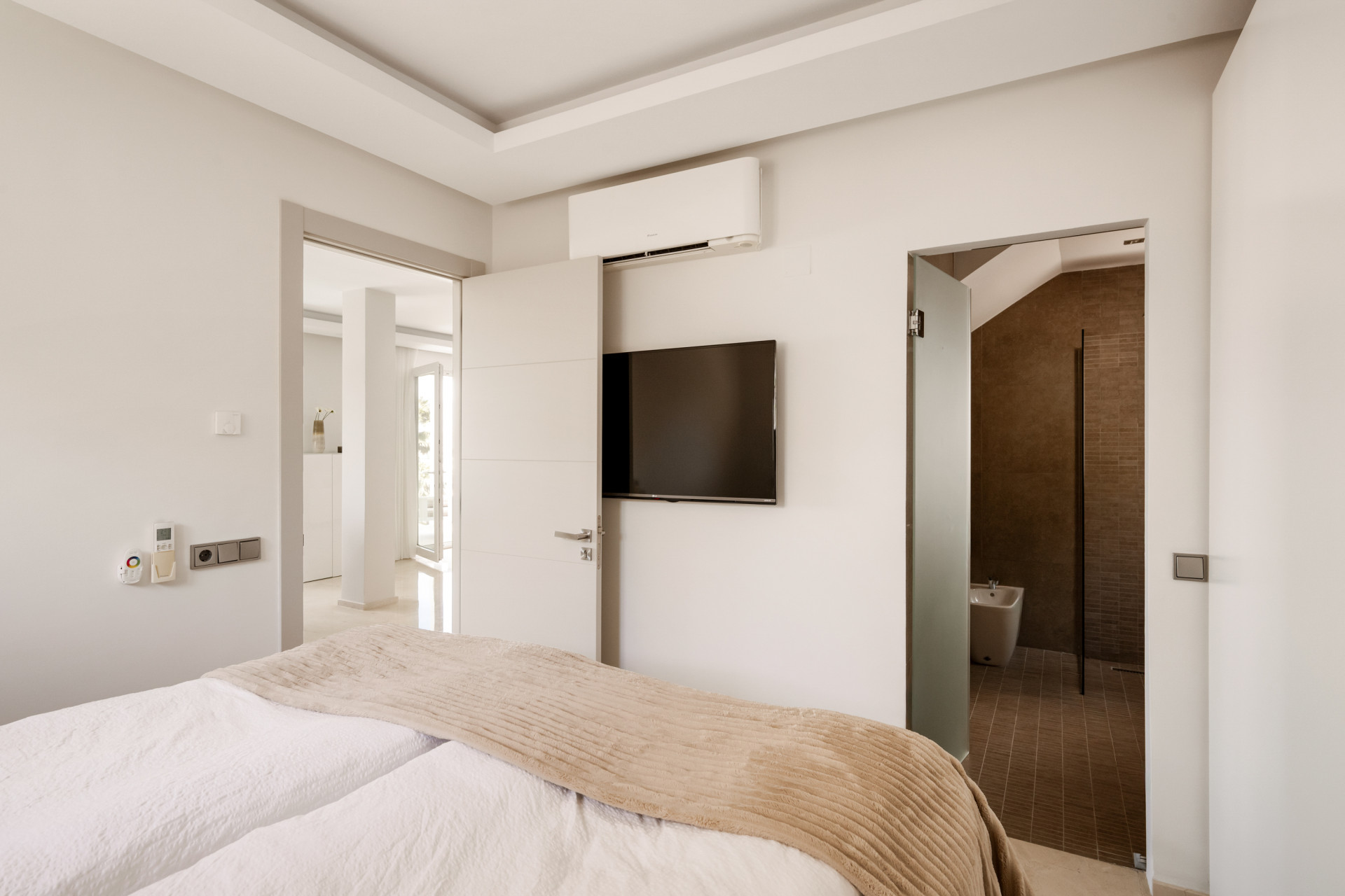 Bedroom features a TV mounted on the wall and an open door leading to a bathroom.