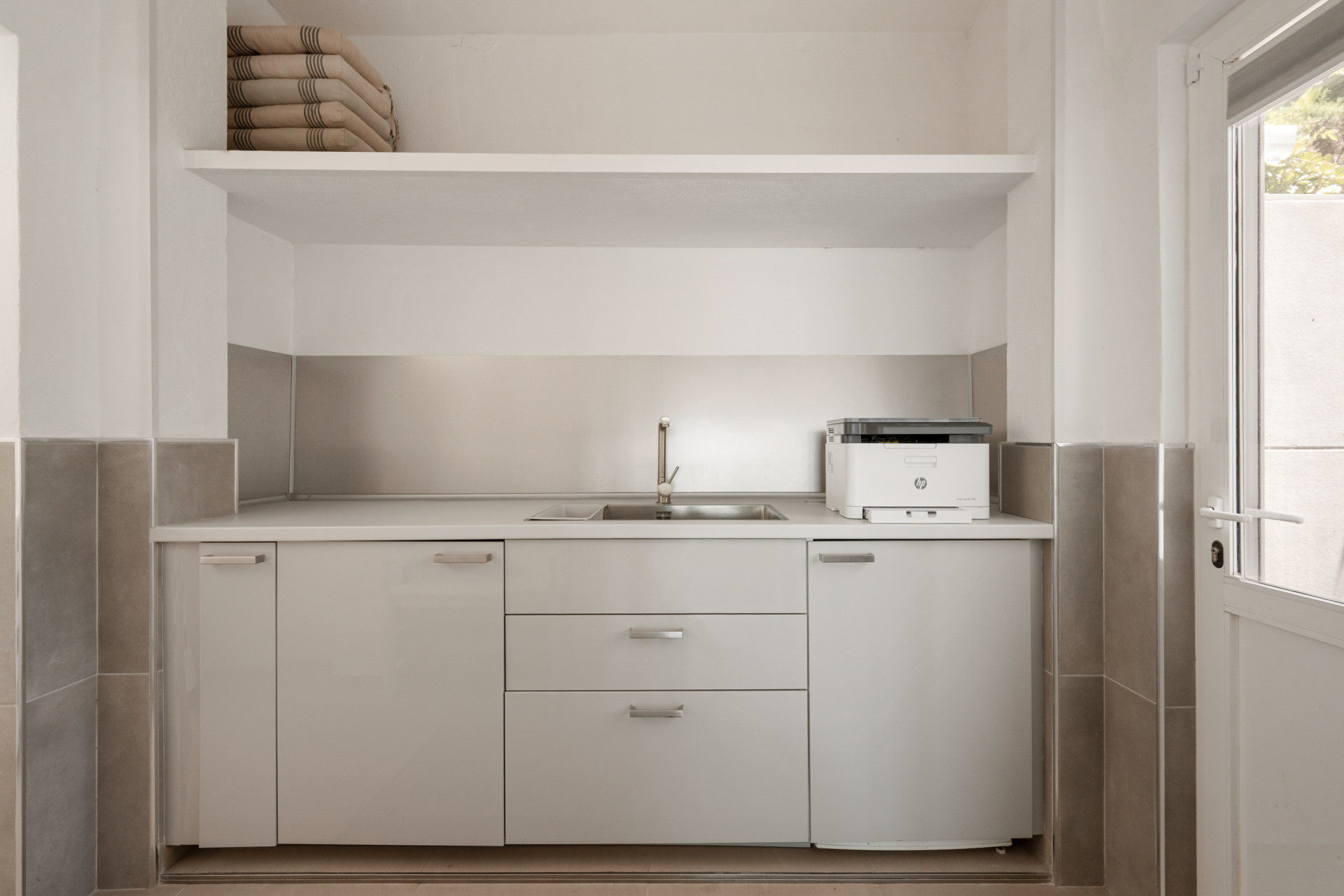 Functional laundry room with sink, cabinets, and printer, accessible through a door.