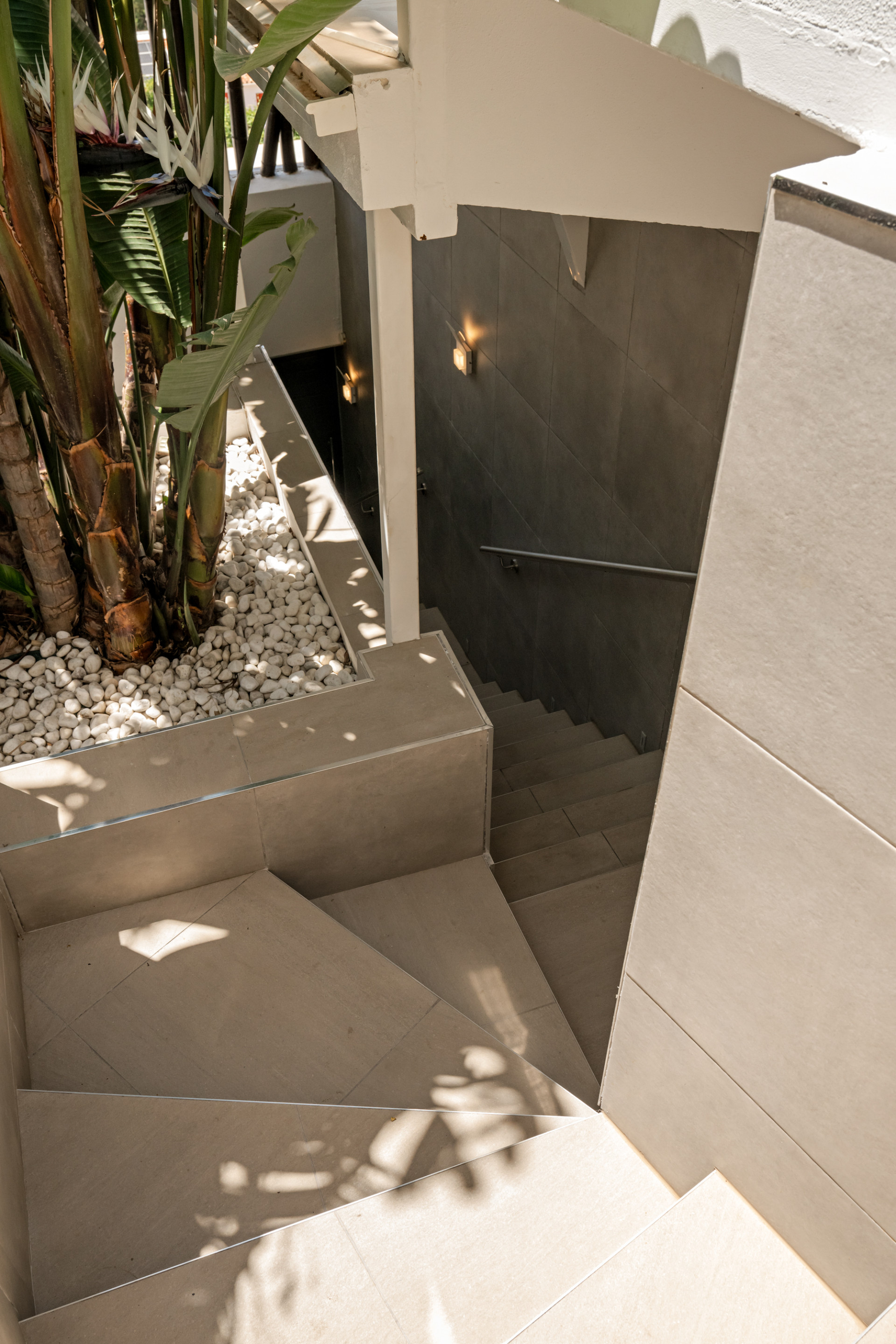 Staircase leading down with greenery and decorative stones on the side.